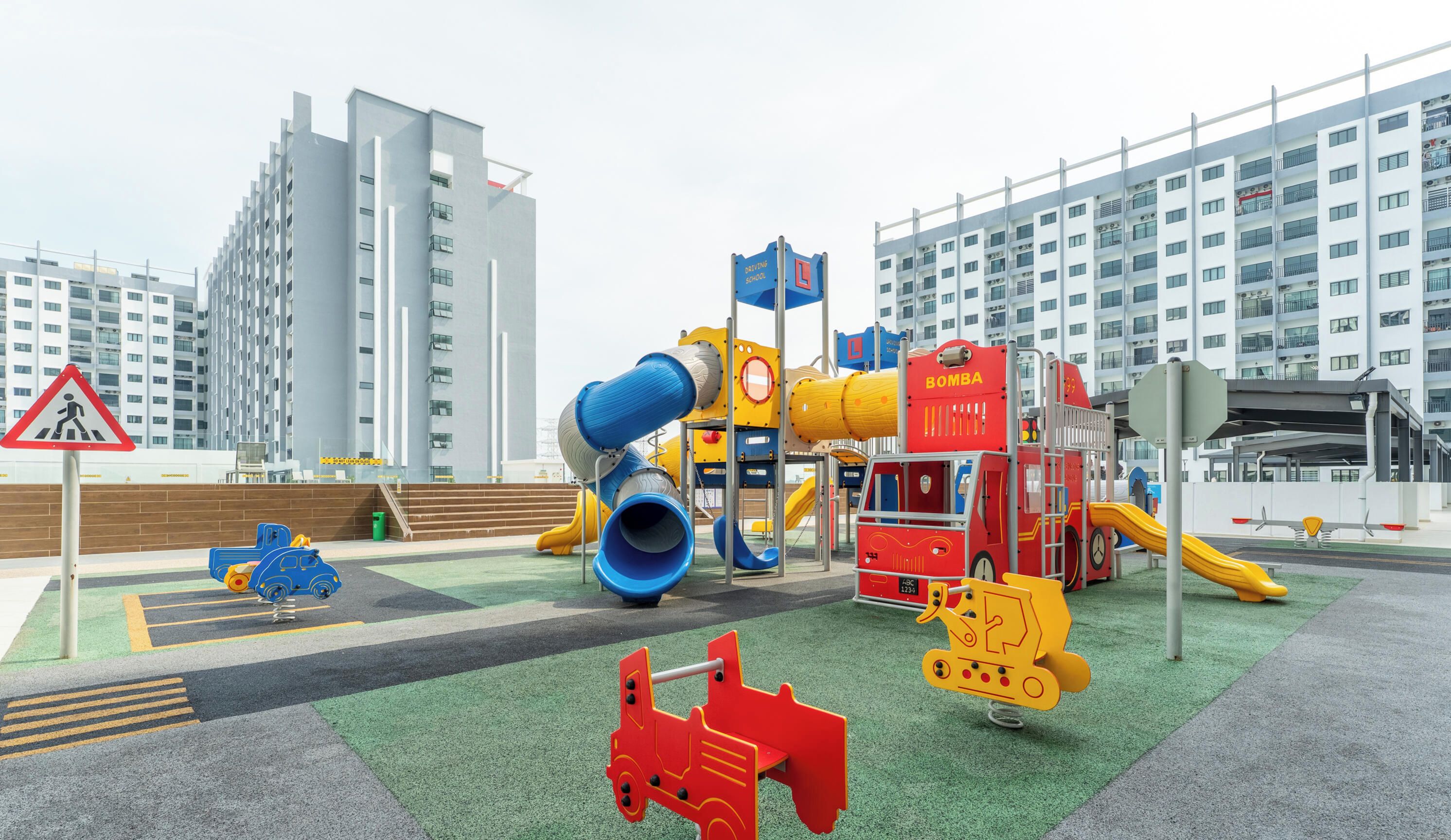 A playground with slides and climbing structures, surrounded by modern buildings.