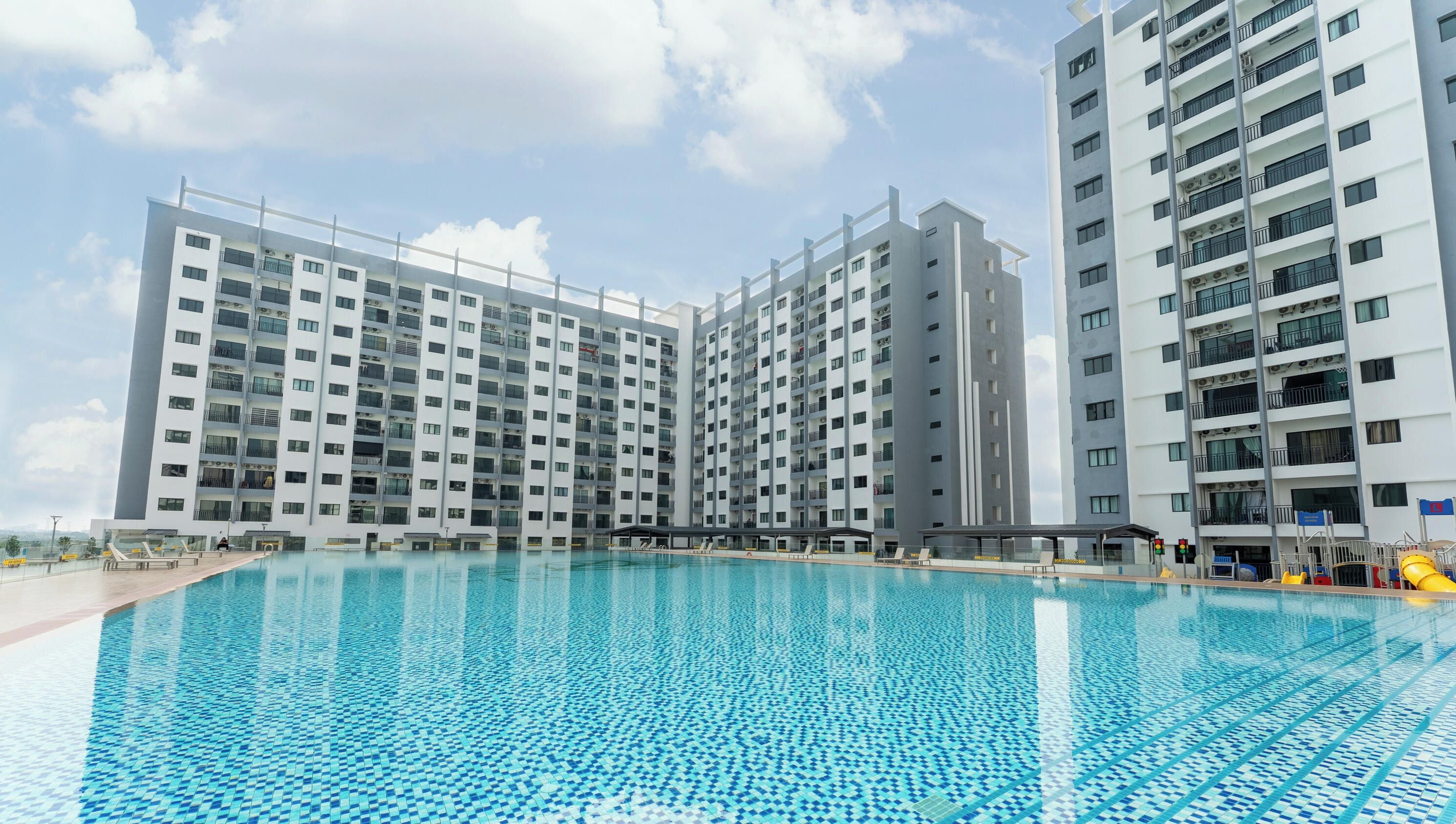 A modern apartment building with a swimming pool in front.