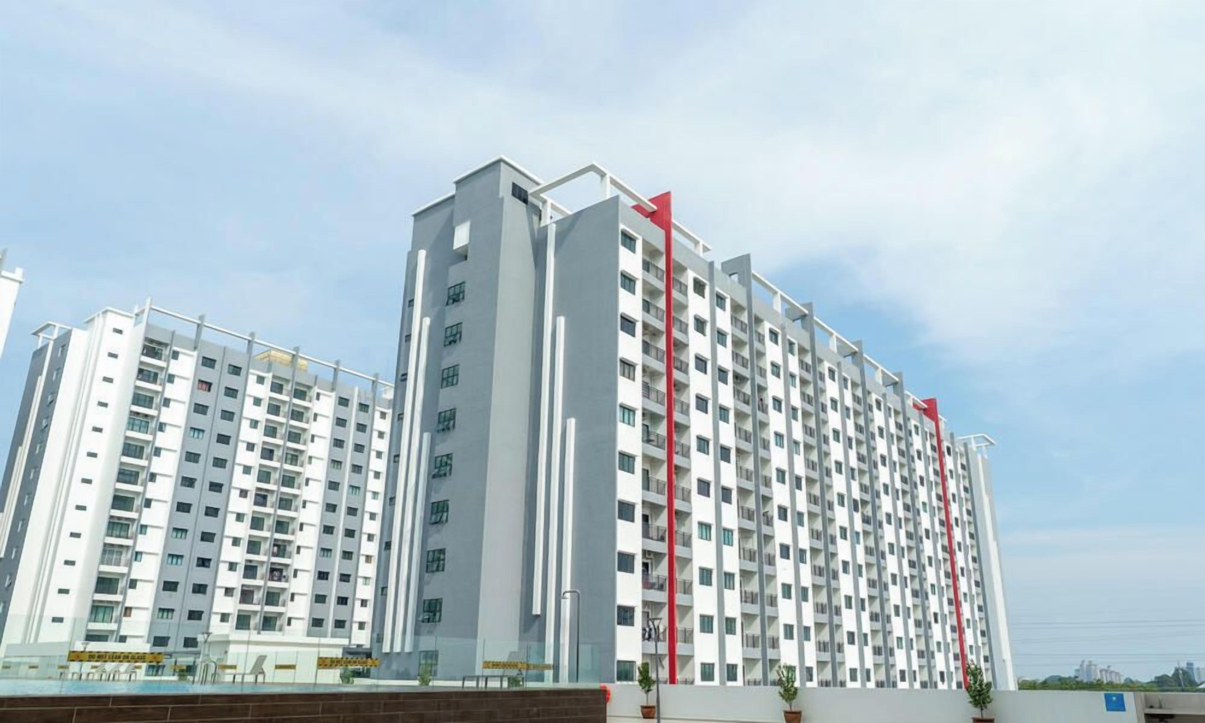 A multi-story residential building with a modern architectural design, featuring balconies and a prominent red vertical element.