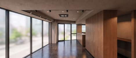 A modern hallway with large windows, a wooden reception desk, and recessed lighting.