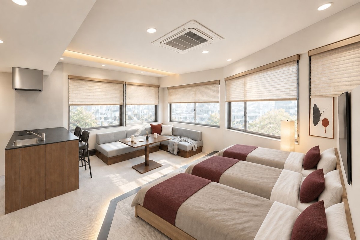A modern hotel room with a kitchenette, a sofa, a bed, and large windows.