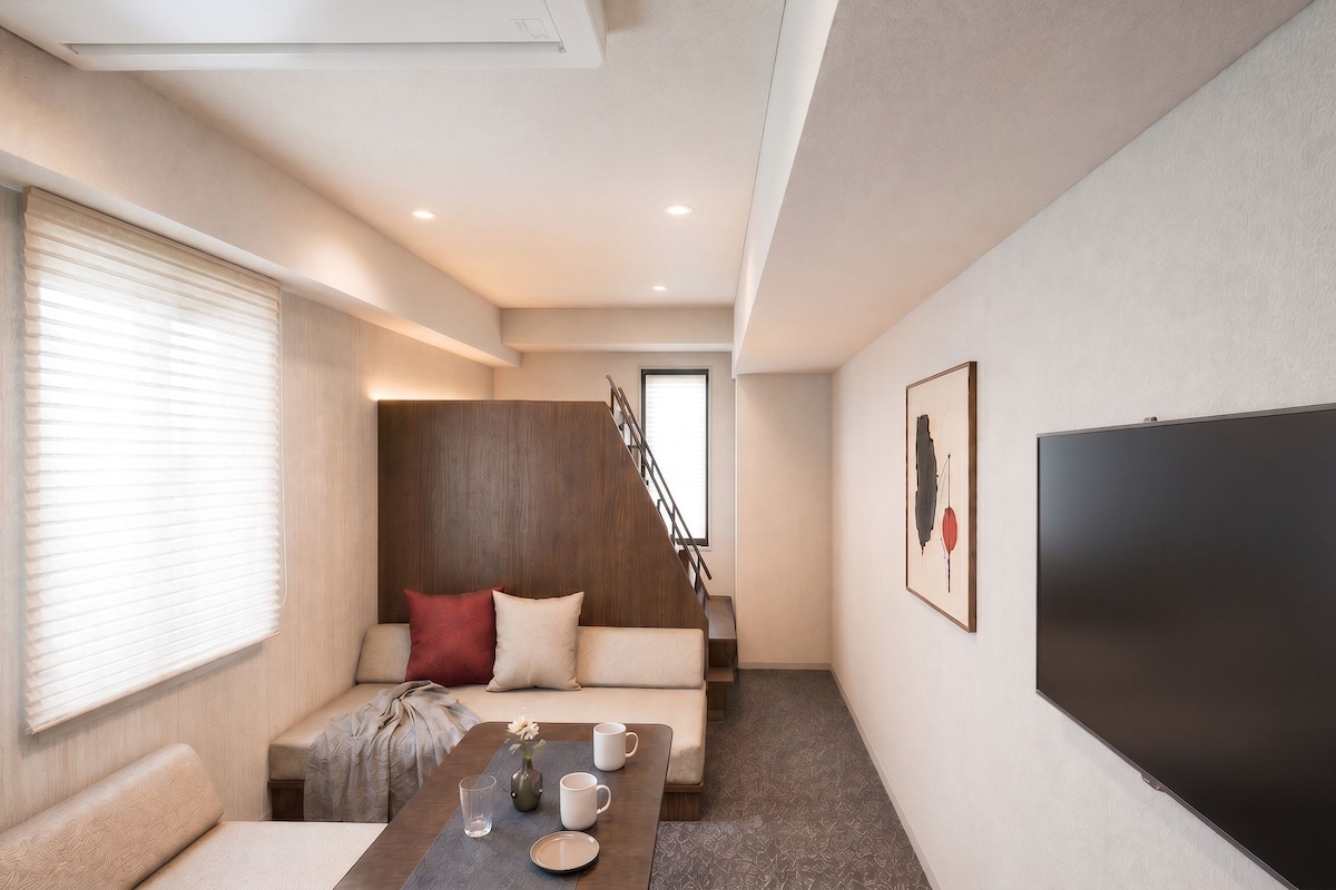 A modern living room with a sofa, a coffee table, and a flat-screen TV.