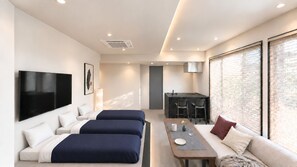 Habitació d'hotel moderna amb llit, sofà, zona de menjador i televisió.