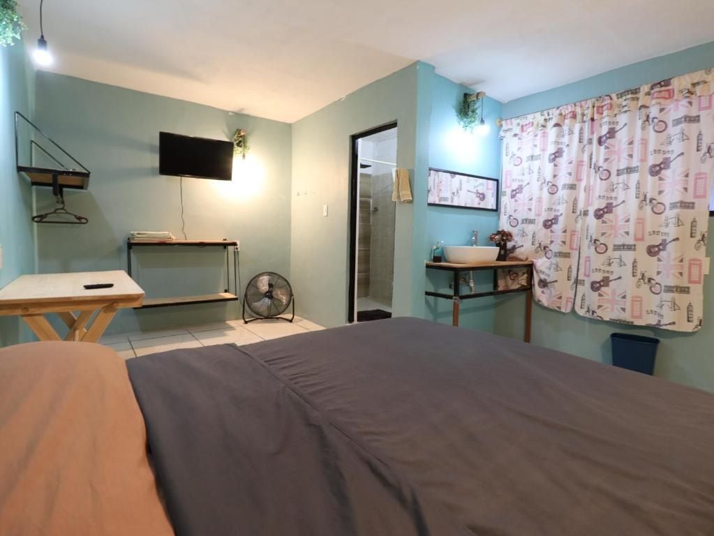 Un dormitorio con cama, mesita de noche y televisor montado en la pared.
