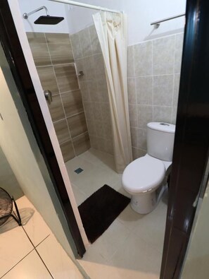 A bathroom with a shower, toilet, and a black mat on the floor. - Casa Corazon Centro (Oaxaca de Juárez)