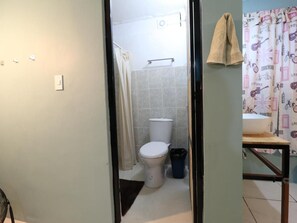 A bathroom with a toilet, shower, and a sink with a towel hanging on the wall. - Casa Corazon Centro (Oaxaca de Juárez)