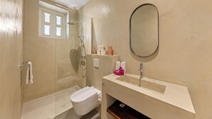 A bathroom with a shower, toilet, sink, and a mirror. - Vrbo Property (Willemstad)