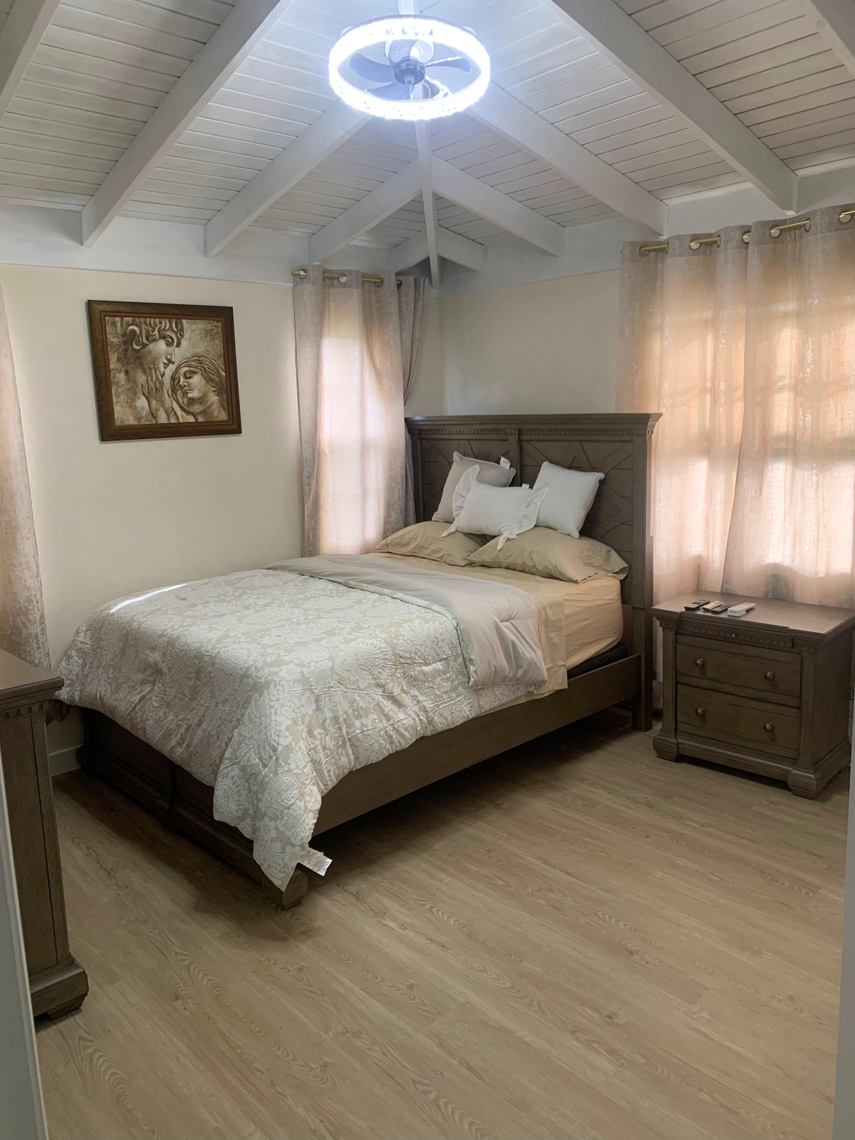 A bedroom with a bed, nightstand, and a ceiling fan.