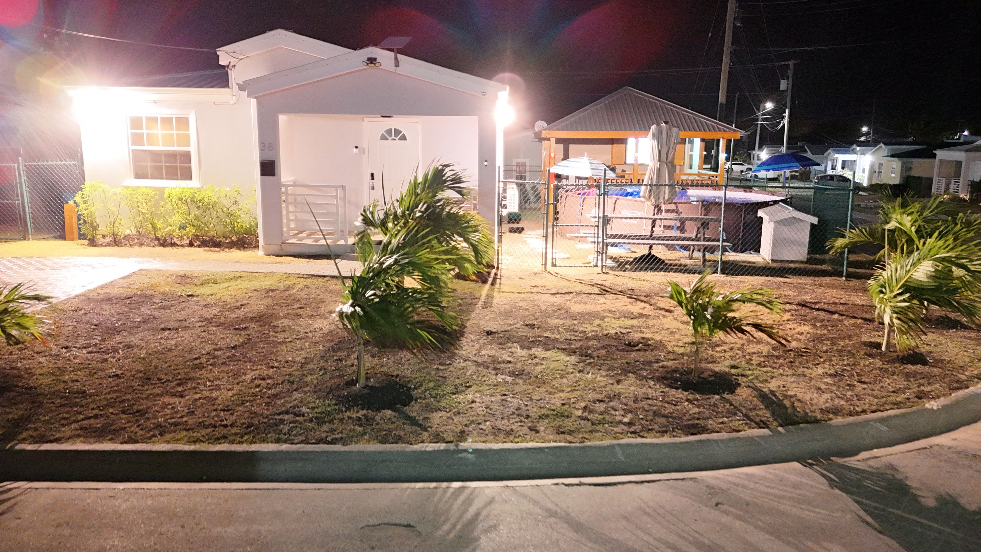 A fenced outdoor area with a small building, possibly a utility or storage shed, and a covered structure with a roof.