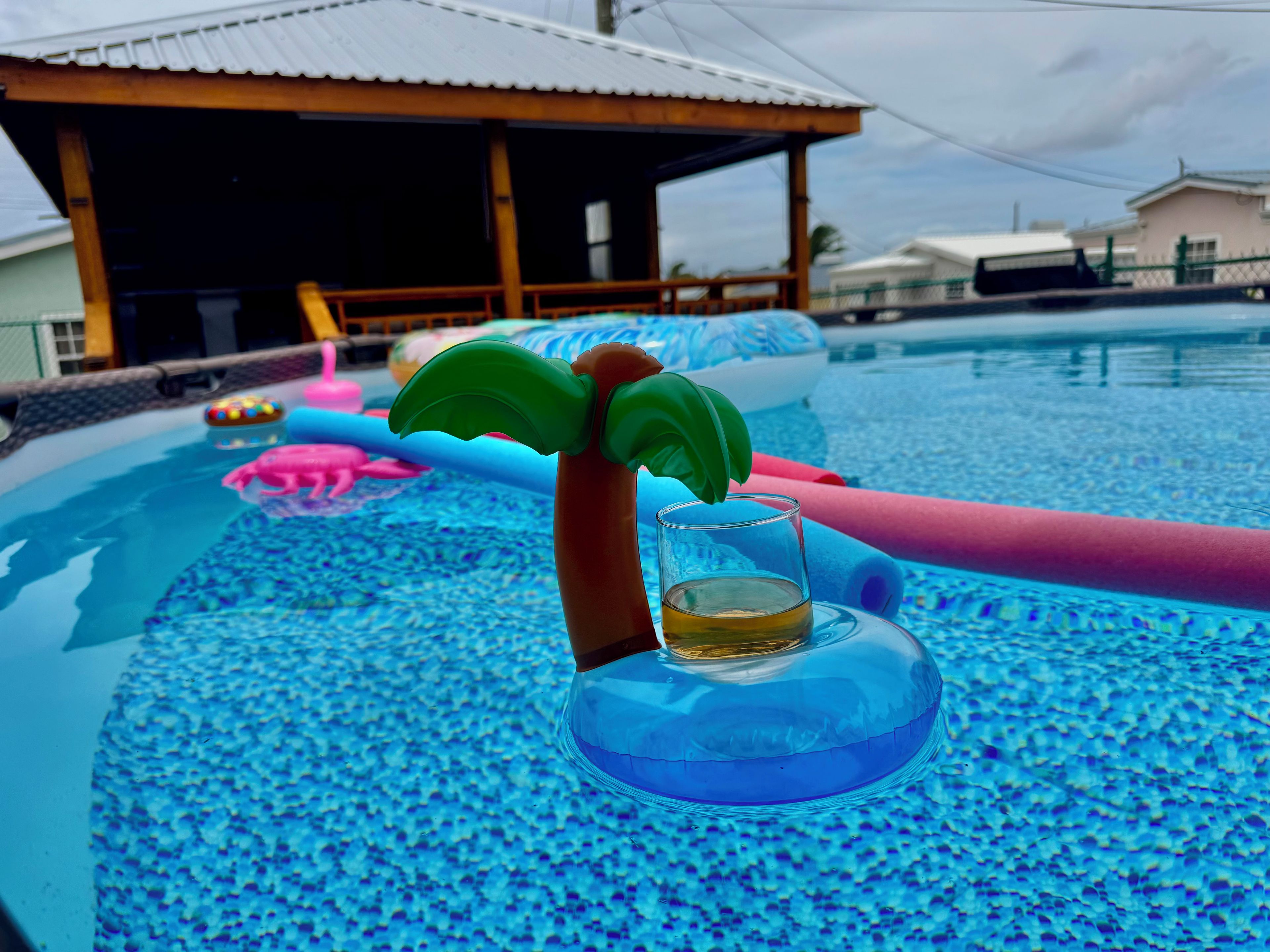 Una piscina con juguetes inflables y un vaso de líquido.