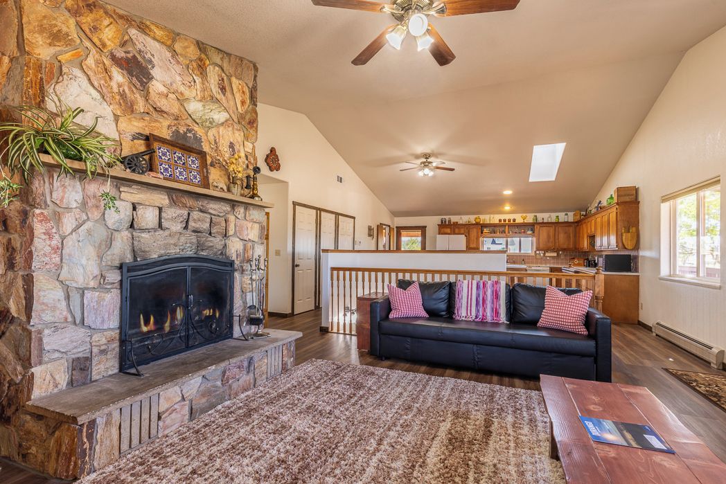 A spacious living area with a stone fireplace, a black leather sofa, and a wooden coffee table.