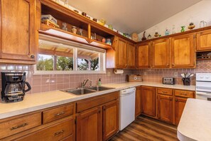 Eine Küche mit Holzausstattung, einer Kaffeemaschine, einem Geschirrspüler und einem Toaster.