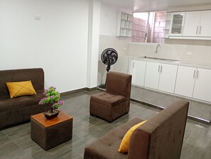 Een moderne woonkamer met een bank, fauteuil en een kleine tafel met een plant.