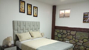 A bedroom with a bed, bedside tables, a lamp, a stone wall, and artwork on the wall. - An Airbnb-style vacation rental, perfect if you're visiting Podocarpus Park. (Zamora)