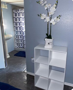 A bathroom with a white pedestal shelf holding a potted orchid, a patterned shower curtain, and a white sink. - 3-bedroom mobile home in beautiful Eagle Pass with AC (Eagle Pass)