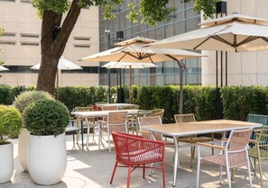 An outdoor patio with tables and chairs, surrounded by potted plants and umbrellas. - Yiwu Ocean Hotel  (Jinhua)