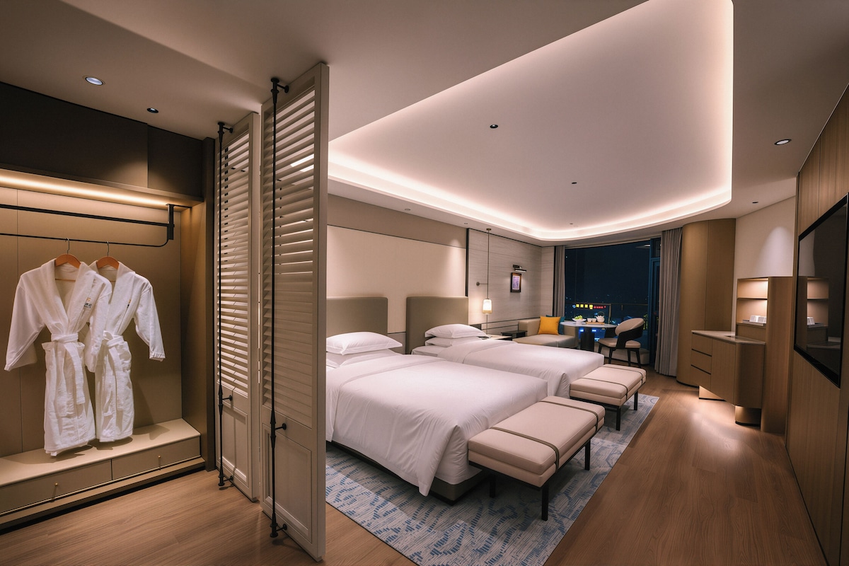 A hotel room with two beds, a desk, and a seating area.