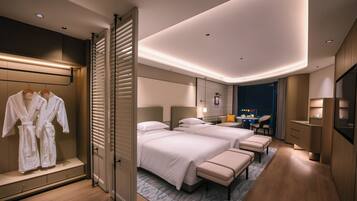 A hotel room with two beds, a desk, and a seating area.