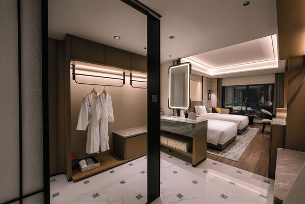 A modern hotel room with a large bed, a sitting area, a bathroom, and a wardrobe with hanging robes. - Yiwu Ocean Hotel  (Jinhua)