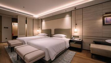 A hotel room with a large bed, two bedside tables, a desk, a chair, and a small bench.