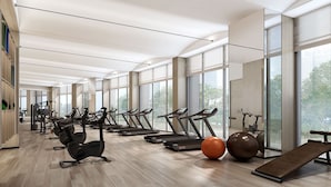 Un gimnasio moderno con cintas de correr, bicicletas estáticas y pelotas de ejercicio.
