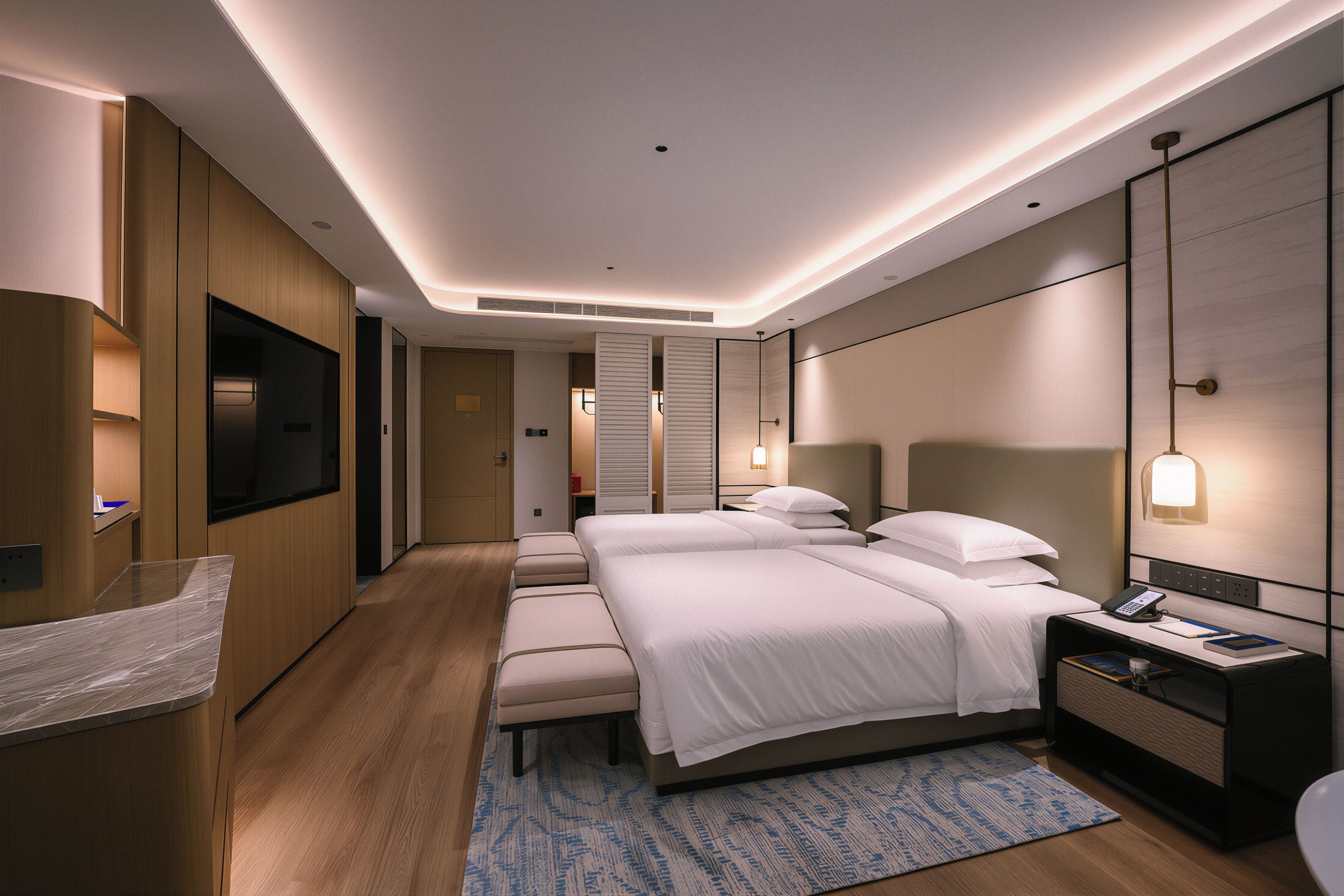 A modern hotel room with a large bed, bedside tables, a desk, and a television.