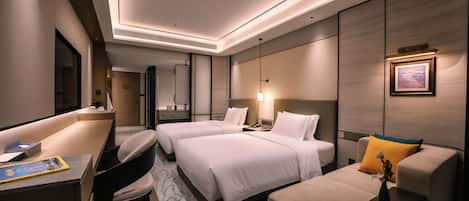 Una habitación de hotel moderna con una cama grande, un escritorio, un sofá y una mesa de comedor.