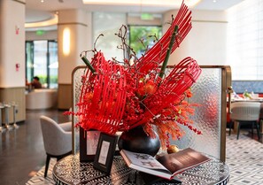 A modern interior with a decorative red plant arrangement on a table, a framed picture, and a book.