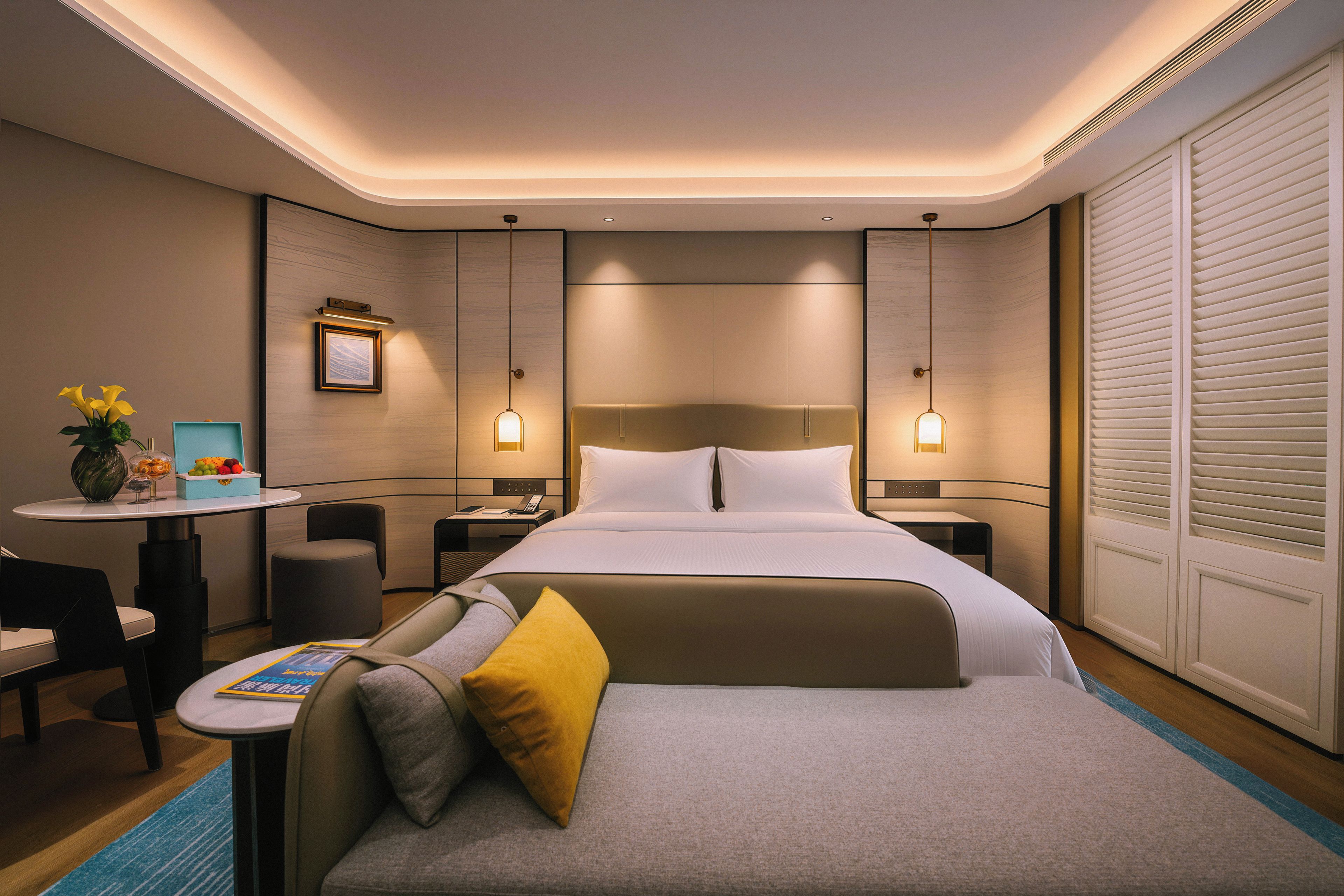 Une chambre d’hôtel moderne avec un grand lit, des tables de chevet, un bureau et une chaise.