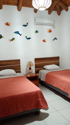 A hotel room with two beds, a nightstand with a lamp, and a wall decorated with fish decals. - Valles deOlon - Ecuador Peaceful 3-bedroom house with AC charming Ruta del sol (santa elena)
