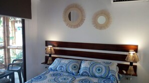 A bedroom with a bed, two bedside lamps, and two wall-mounted mirrors.