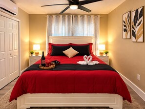 A hotel room with a bed, a ceiling fan, a window with curtains, bedside lamps, and wall art. - Modern Private Suite Pet Friendly,Near Busch Gardens (Tampa)