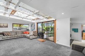 A modern living room with a sectional sofa, a large painting, and a sliding glass door leading to an outdoor area.