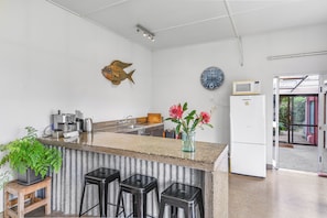 Een keuken met een bar, een klok, een decoratie van een vis en een koelkast.