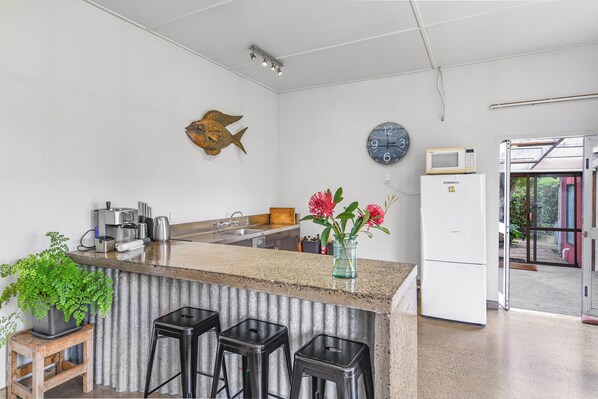 A kitchen with a bar area, a clock, a fish decoration, and a refrigerator.