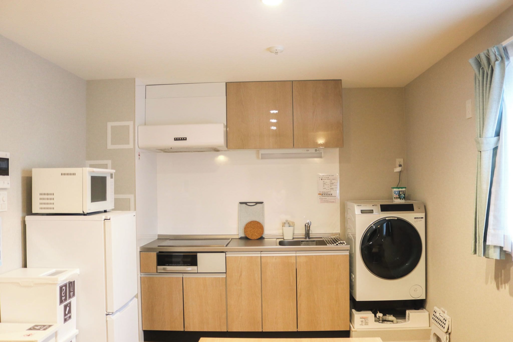 Uma cozinha compacta equipada com micro-ondas, cafeteira, máquina de lavar e frigorífico.