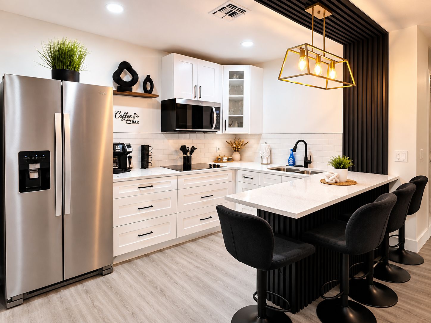 A modern kitchen with a stainless steel refrigerator, white cabinets, a central island with bar stools, and a hanging light fixture.