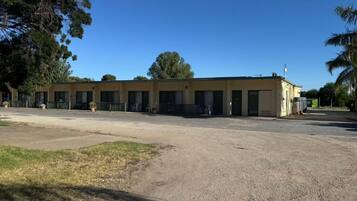A building with a row of rooms, a parking lot, and a clear sky.