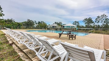 A pool area with lounge chairs and a picnic table.