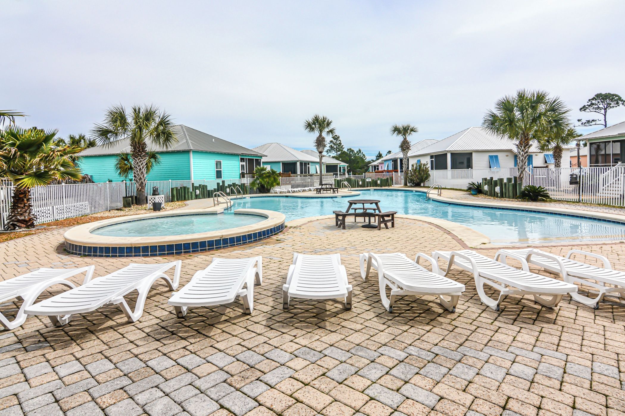 A pool area with lounge chairs and a hot tub.