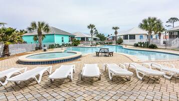 A pool area with lounge chairs and a hot tub.