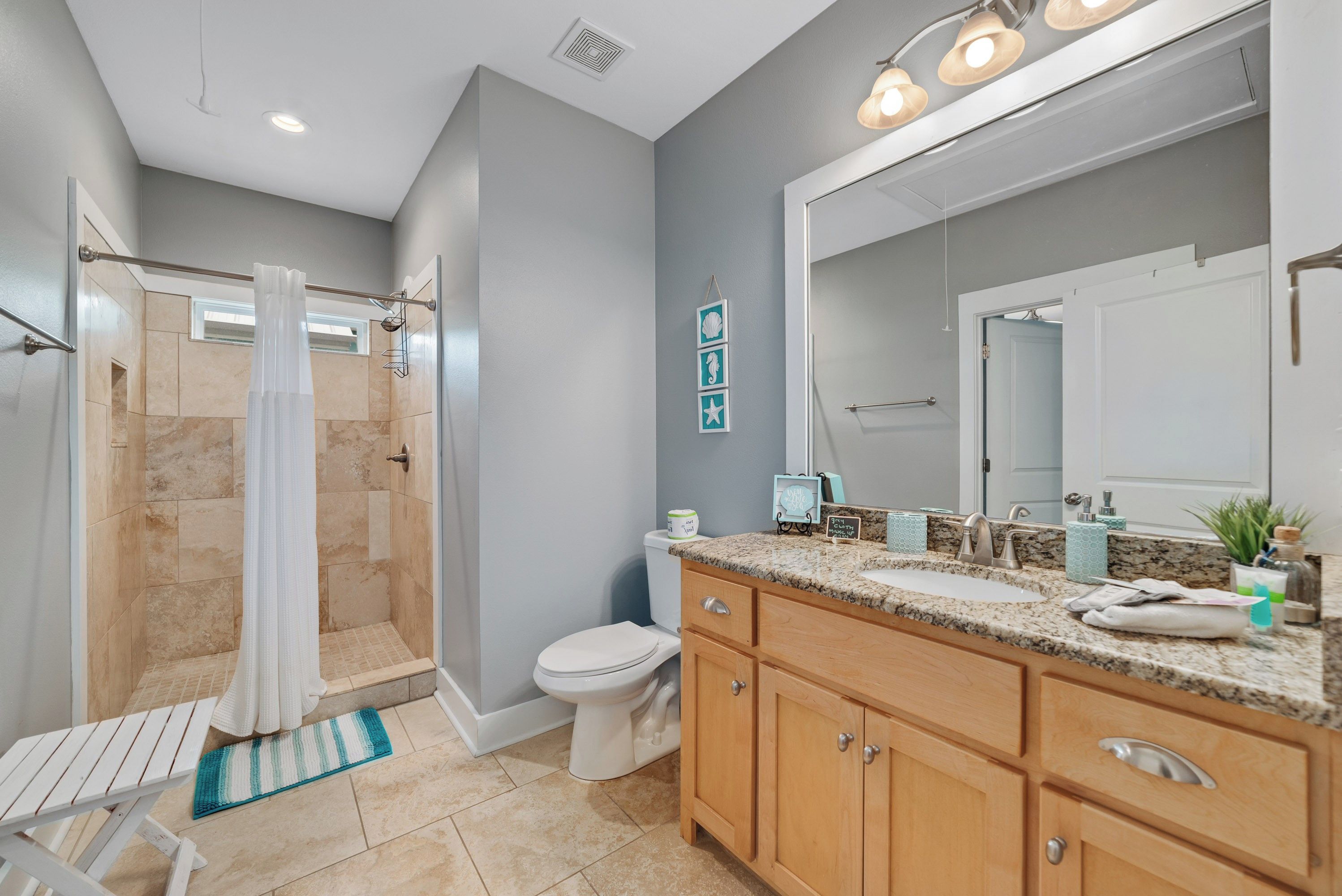 Une salle de bain moderne équipée d’une douche, de toilettes, d’un meuble-lavabo et d’un grand miroir.