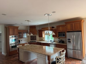 A kitchen with wooden cabinets, stainless steel appliances, a granite countertop, and pendant lighting. - Lakefront Escape with Kayaks & Views (West Milford)