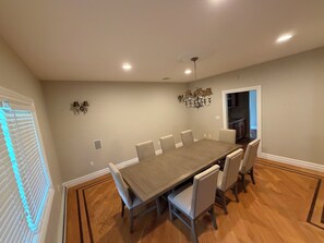 A dining room with a large table, chairs, a chandelier, and a view of the kitchen. - Lakefront Escape with Kayaks & Views (West Milford)
