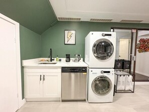 A compact laundry room with a washing machine, a dishwasher, and a countertop with a sink.