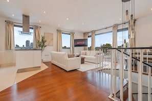 Ein modernes Wohnzimmer mit einer Couch, einem Fernseher und einer Treppe.