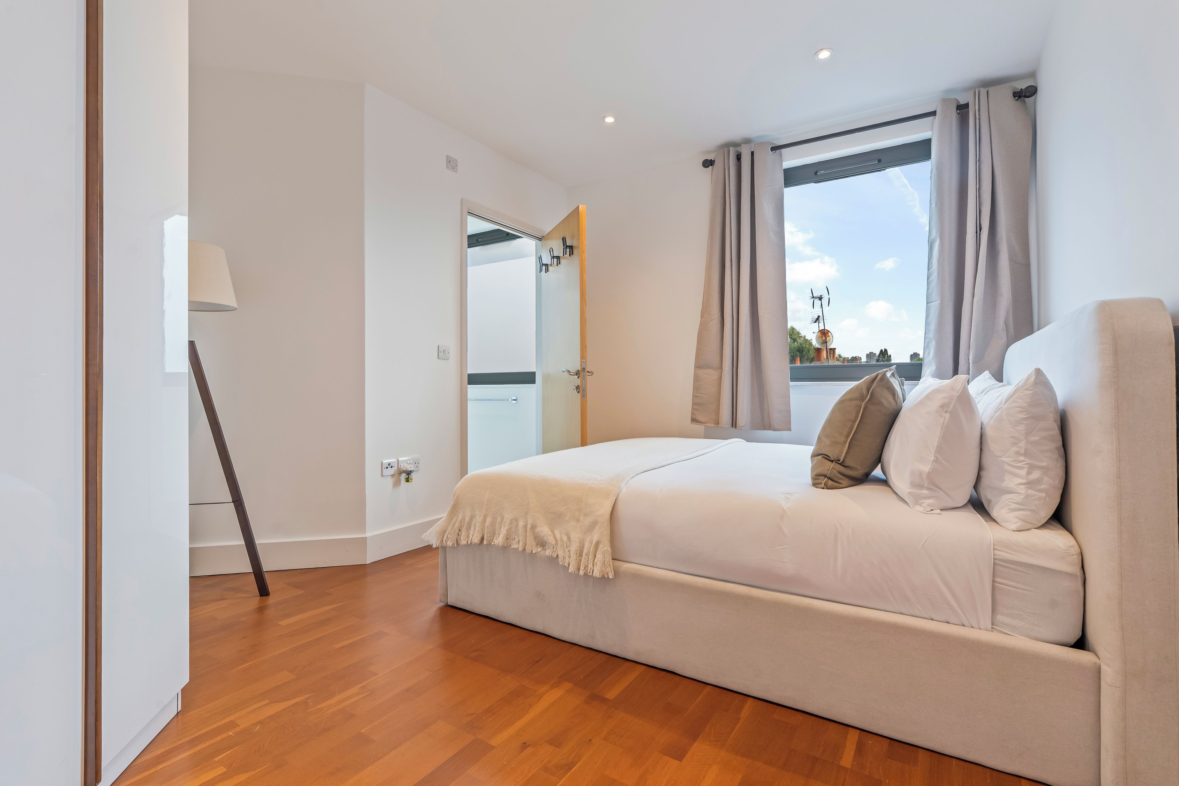 Een slaapkamer met een bed, een lamp en uitzicht.
