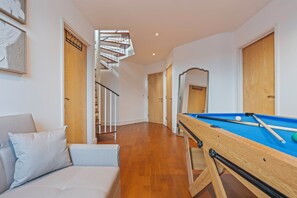 A room with a pool table, a sofa, a staircase, and a door with a mirror. - City View Duplex with Jacuzzi & Snooker Sleeps 10 (London)