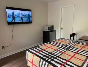 A bedroom with a bed, a television on the wall, a small table, and a door. - Hobson Stay & Residences  (Grand Junction)