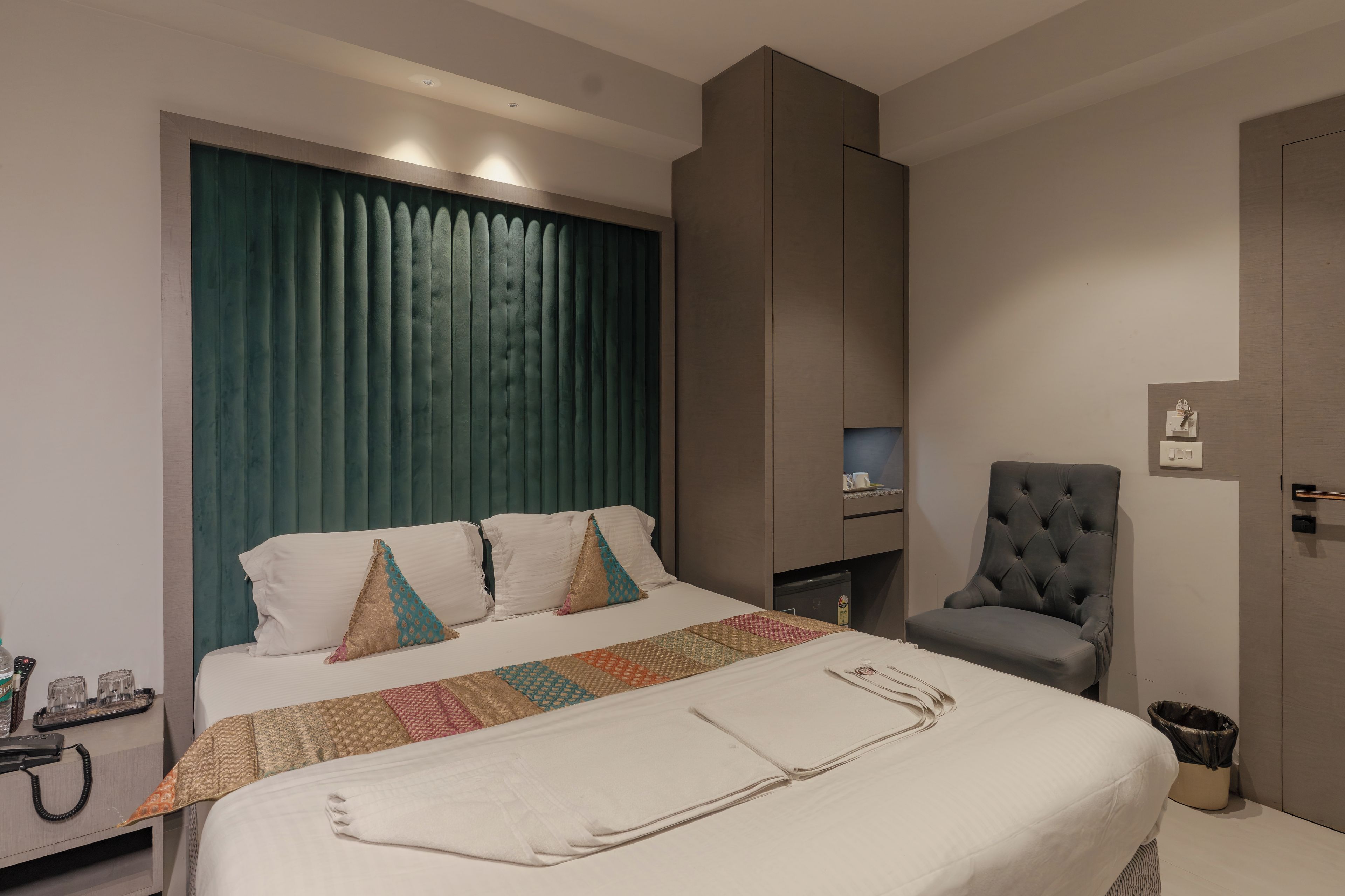Une chambre d’hôtel avec un lit, une chaise, un bureau et une poubelle.